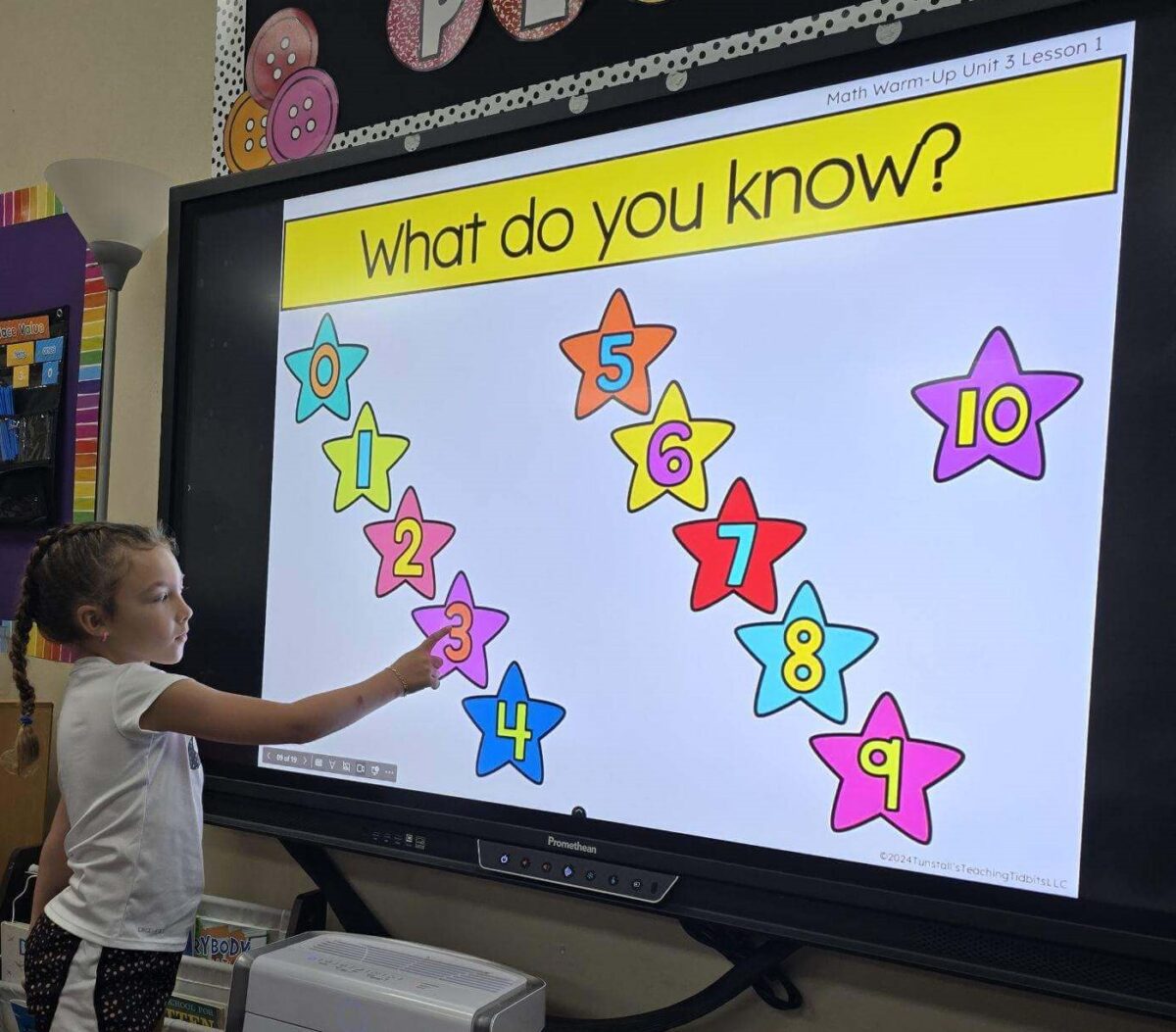 Student at the classroom interactive board counting and ordering numbers as a math warm-up. 