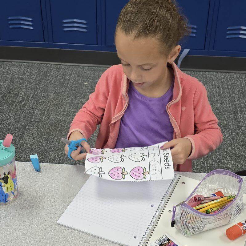 student cutting and gluing a total math learning log page into a math journal.