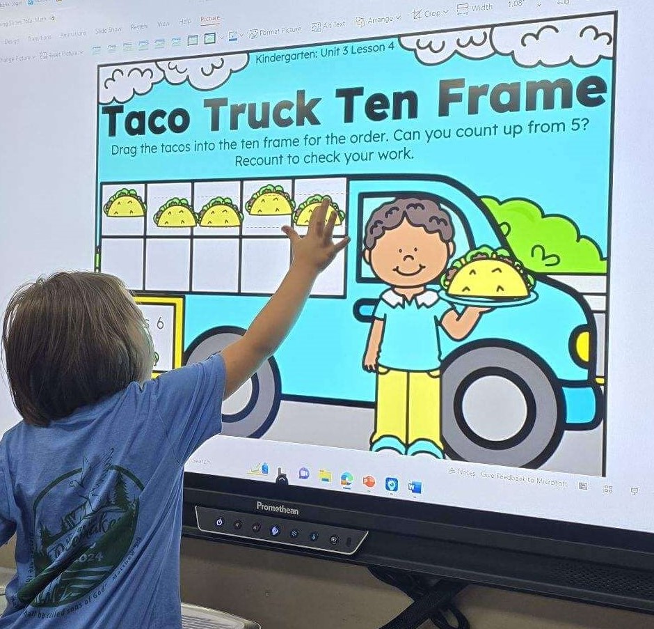 Student counting and building tacos in a ten frame taco truck on a classroom screen to model numbers 6-10. 