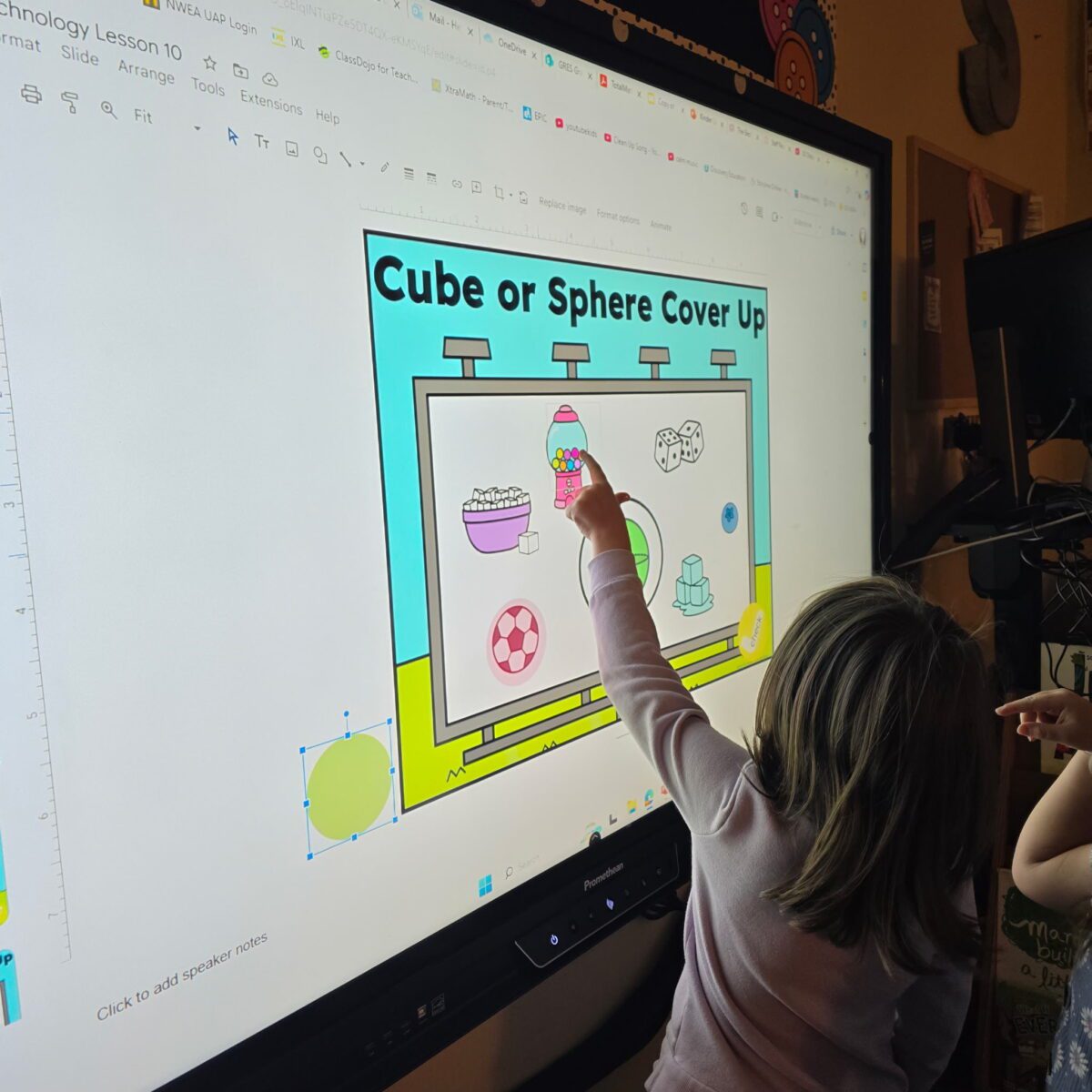 Student identifying three dimensional shapes during a geometry lesson by sorting real world objects as cubes or spheres in a K 2 classroom
