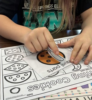 First grade students cutting cookie shapes into equal parts.