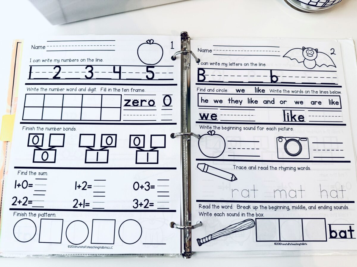 First grade daily math and daily language spiral review worksheets in a binder featuring addition practice, number bonds, sight words, and phonics activities